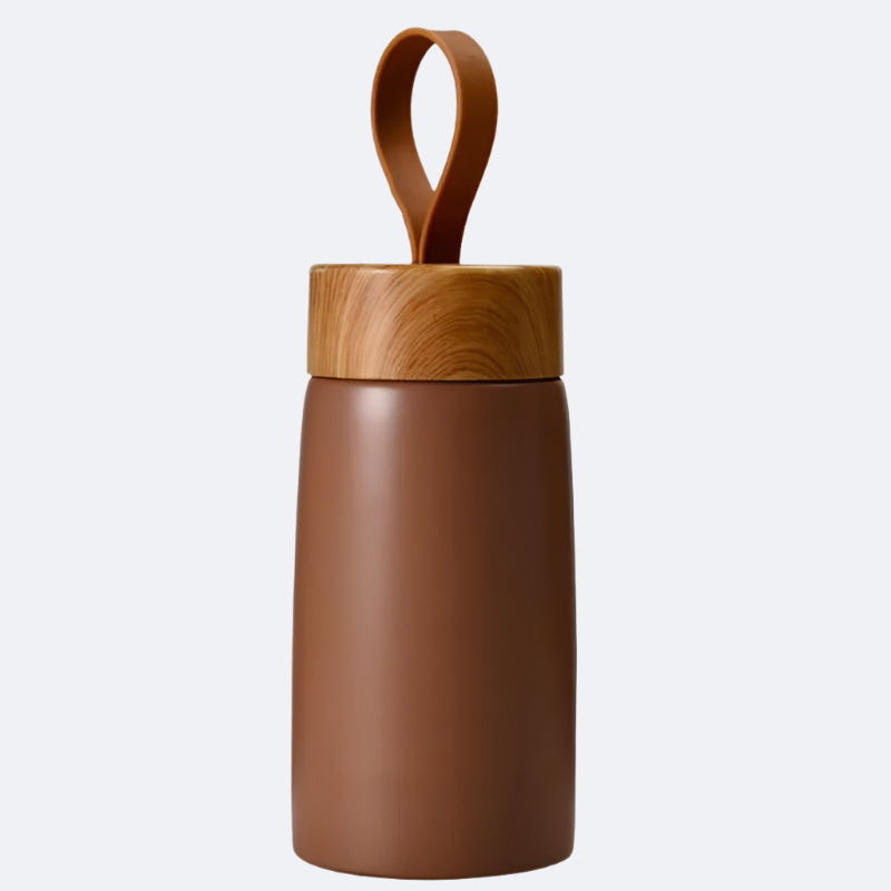 A brown-colored cylindrical bottle with a wooden lid and a carrying handle on top, possibly made of bamboo or a similar material.