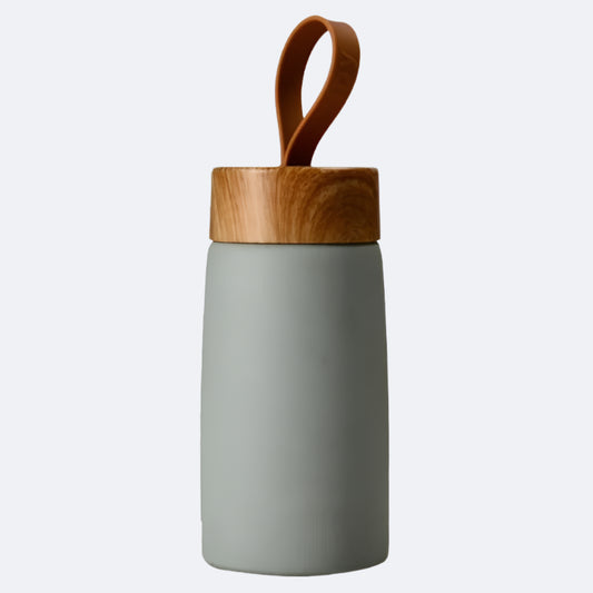 A green-colored cylindrical bottle with a wooden lid and a carrying handle on top, possibly made of bamboo or a similar material.