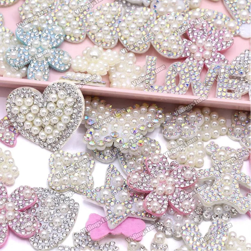 Collection of decorative rhinestone and pearl embellishments on a pink background