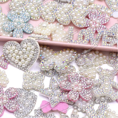 Collection of decorative rhinestone and pearl embellishments on a pink background