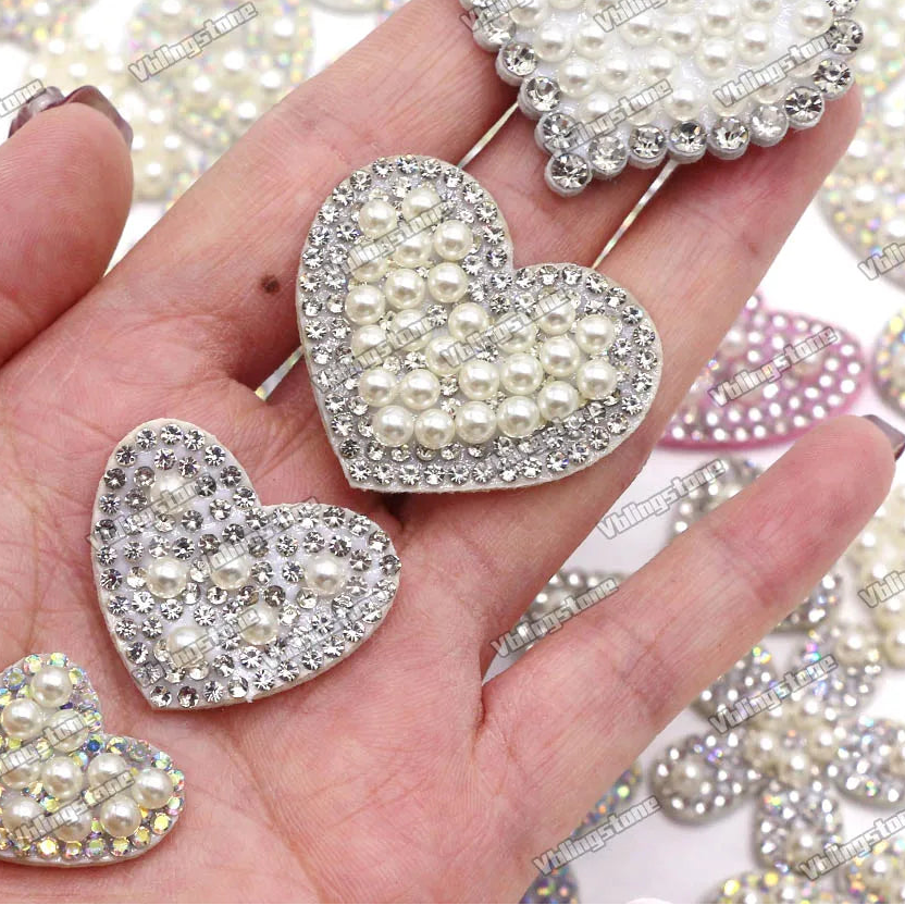 Heart-shaped jewelry pieces with pearls and crystals on a hand, with 'Vlingstone' branding.
