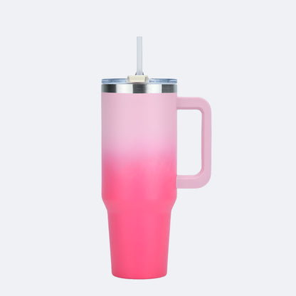 A gradient-colored tumbler with a handle and straw lid, transitioning from green at the top to pink at the bottom.