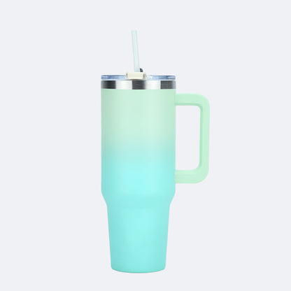 A gradient-colored tumbler with a handle and straw lid, transitioning from green at the top to pink at the bottom.