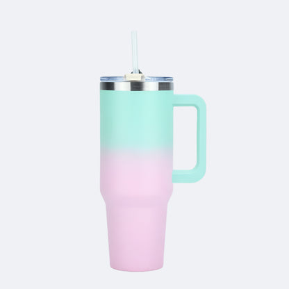 A pink-green stainless steel tumbler with a handle and a straw lid, displayed against a plain background.