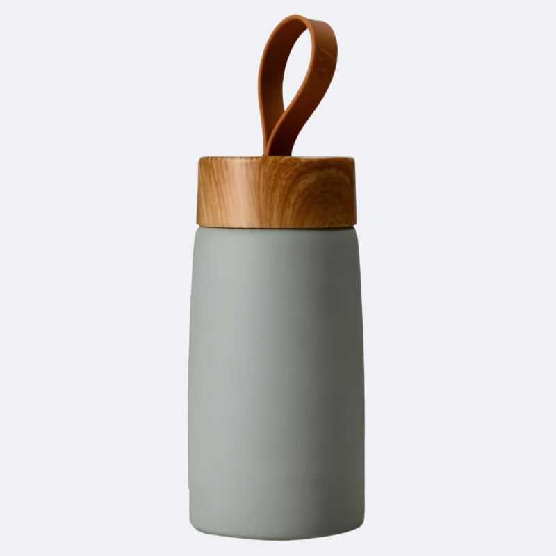 A green-colored cylindrical bottle with a wooden lid and a carrying handle on top, possibly made of bamboo or a similar material.