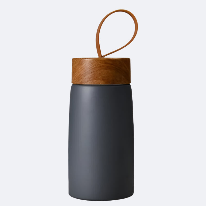 A grey-colored cylindrical bottle with a wooden lid and a carrying handle on top, possibly made of bamboo or a similar material.