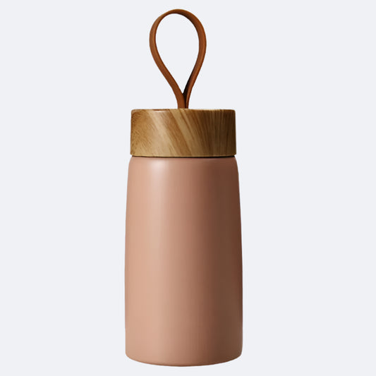 A pink-colored cylindrical bottle with a wooden lid and a carrying handle on top, possibly made of bamboo or a similar material.